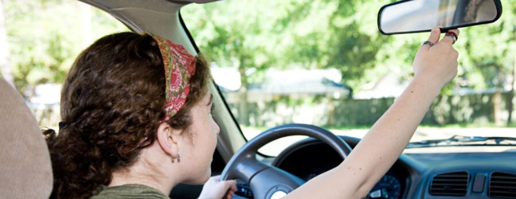 Teen driver adjusting the rearview mirror