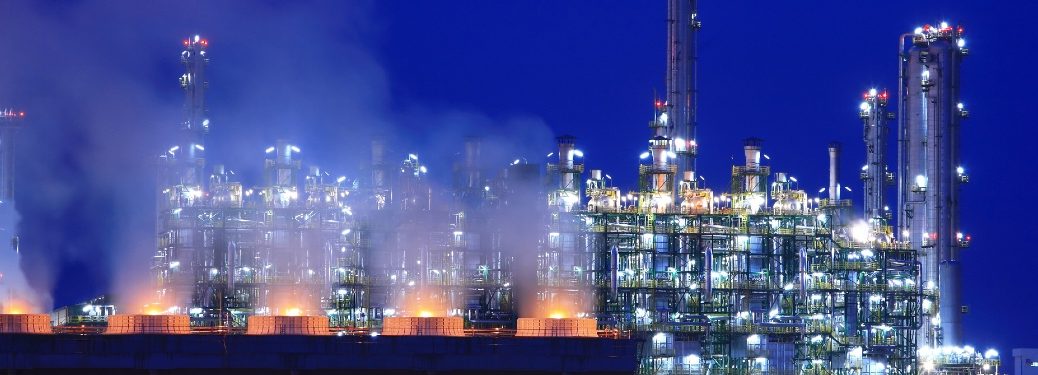 Skyline of an oil refinery at twilight, looking like the backdrop of a Sega Genesis game.