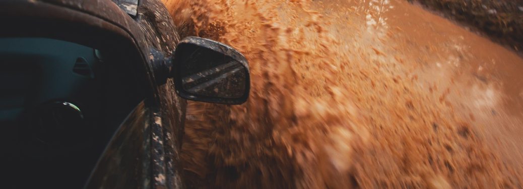 A vehicle drives through deep mud offroad.