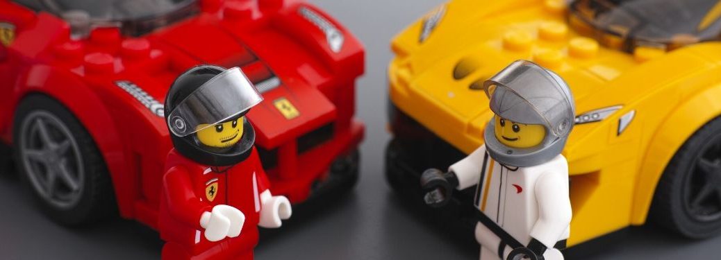 Two lego drivers discuss their lego cars which are parked behind them