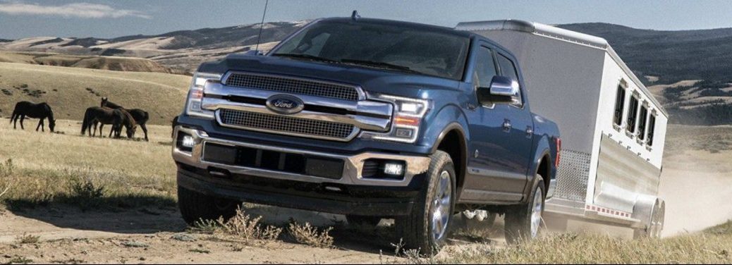 2019 Ford F150 blue exterior towing horse trailer on dirt road
