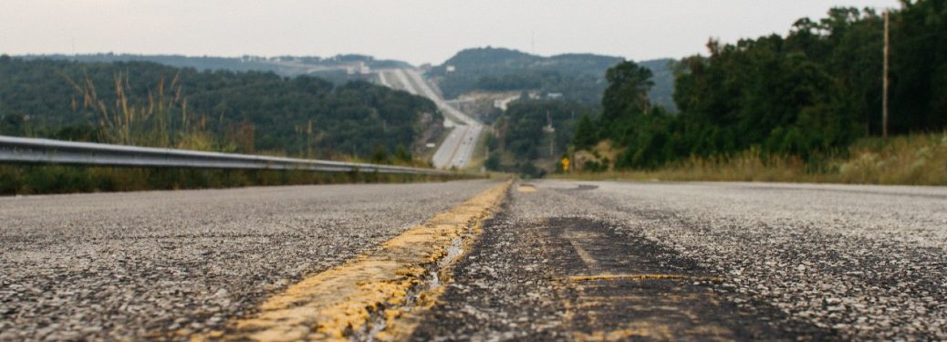 close to highway road on yellow lines trees one side of road