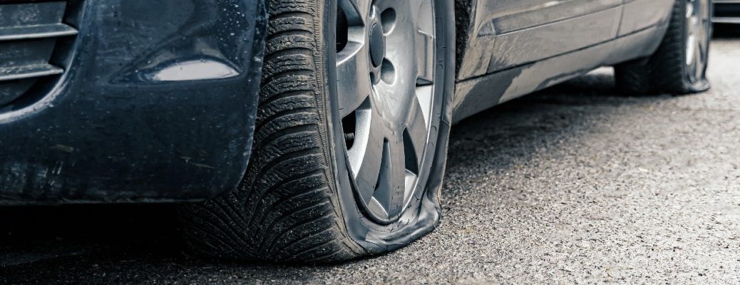 A stock photo of a car with two flat tires.