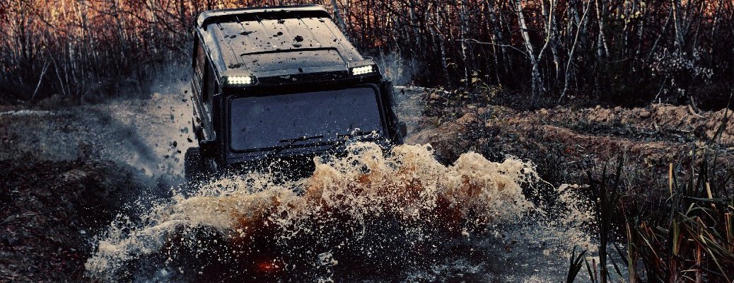 A stock photo of a four-wheel-drive vehicle going through a mud puddle.