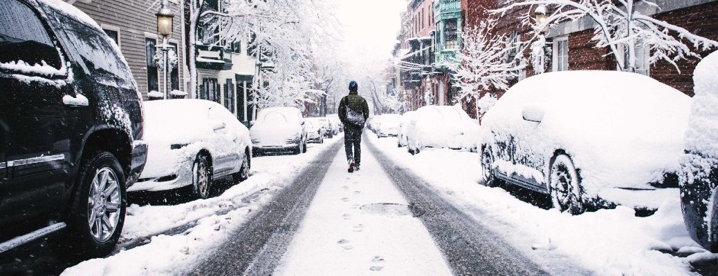 A stock photo of a person walking through snow because their car wouldn't start.