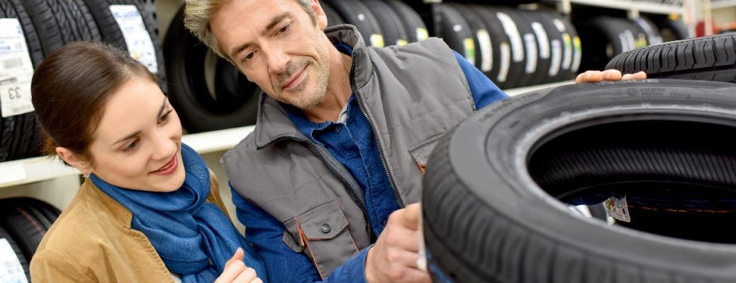 A stock photo of people looking at some tires to buy.