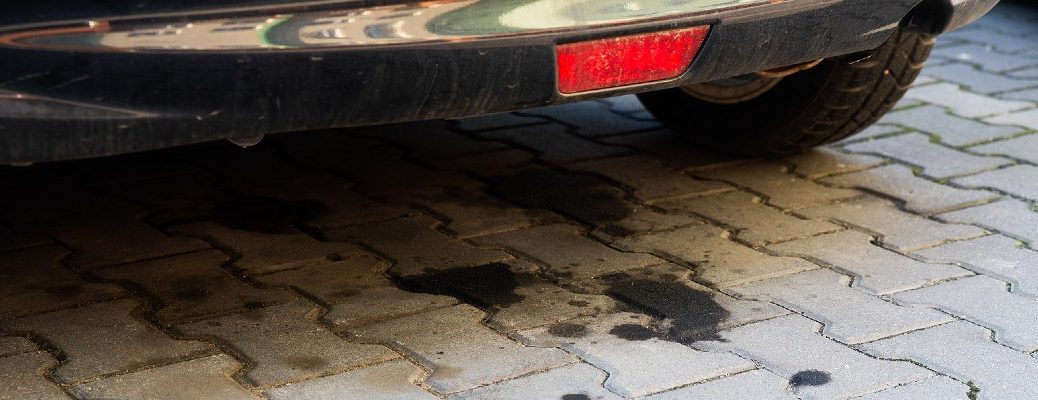 A stock photo of oil spots on a driveway under a car.