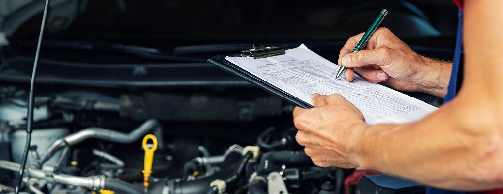 A stock photo of a person using a checklist to inspect a vehicle.