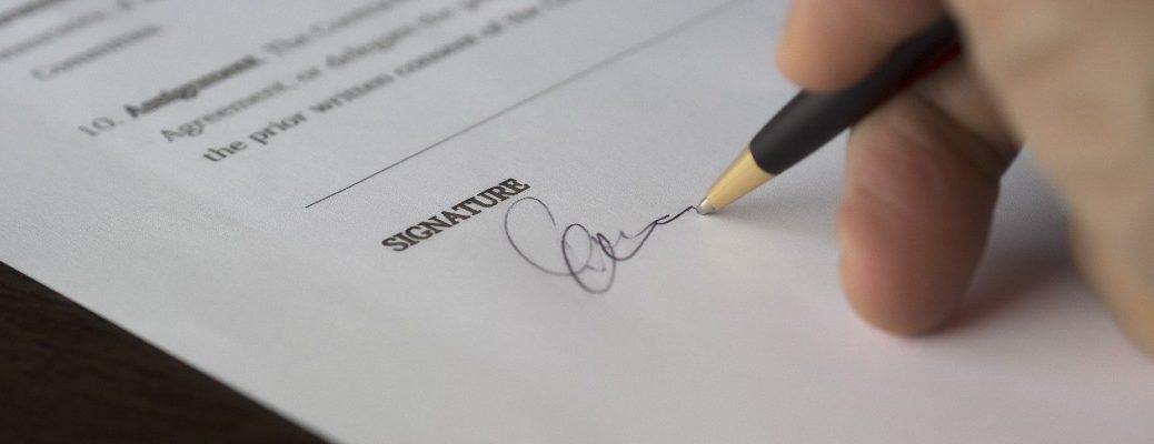 A stock photo of a person signing some paperwork.