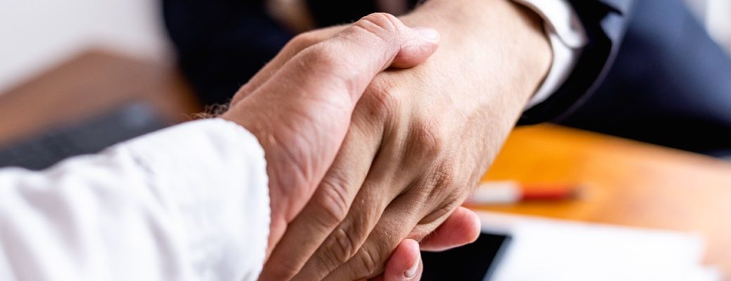 A stock photo of two people shaking hands after completing a deal.