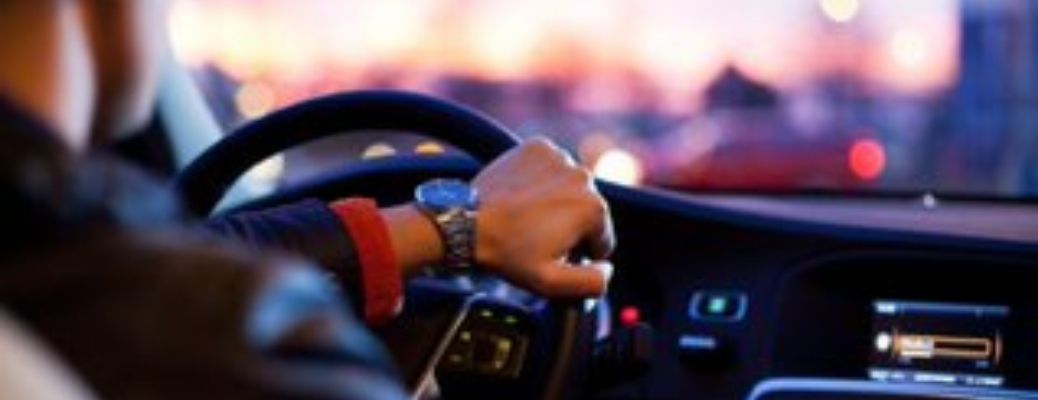 Close up of a hand driving a car at night