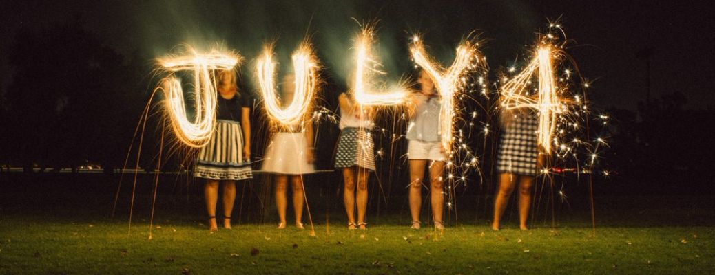 people standing and holding July 4 sign with lights