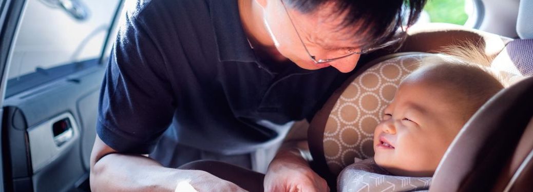 Father is keeping his baby in the car seat.