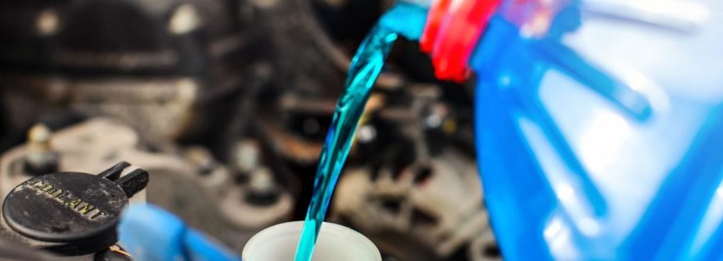Blue color coolant is being poured in the car.