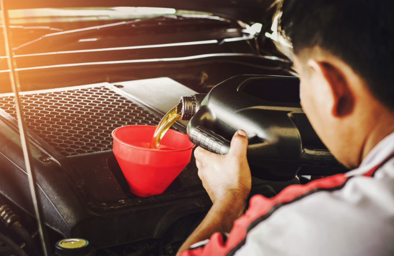 Mechanic pouring oil from a can into a funnel