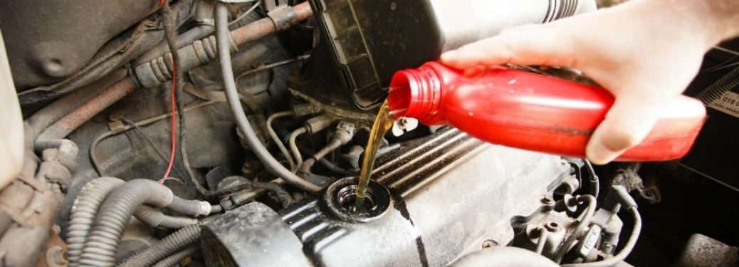 Mechanic pouring oil into a vehicle