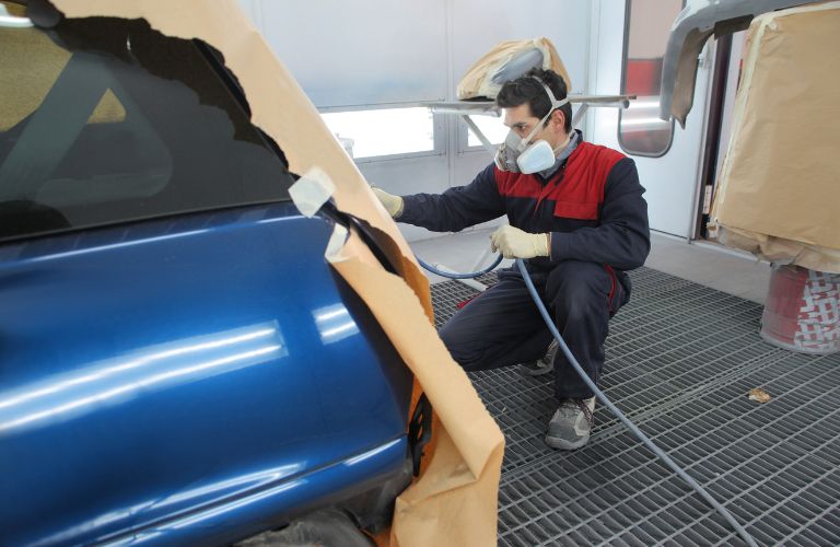 Technician powder coating a vehicle