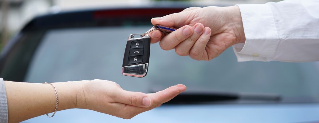 Two hands exchanging a car key