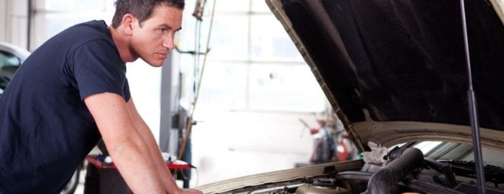Mechanic inspecting under the hood of a vehicle