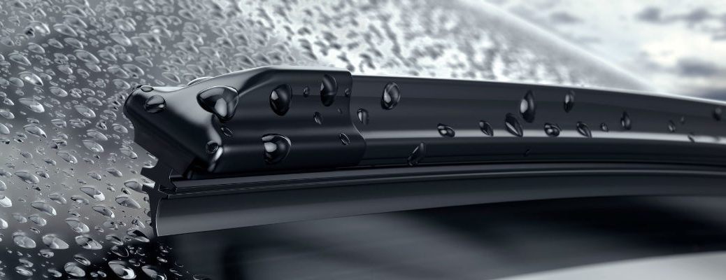 A close up photo of a windshield wiper blade removing water from the glass