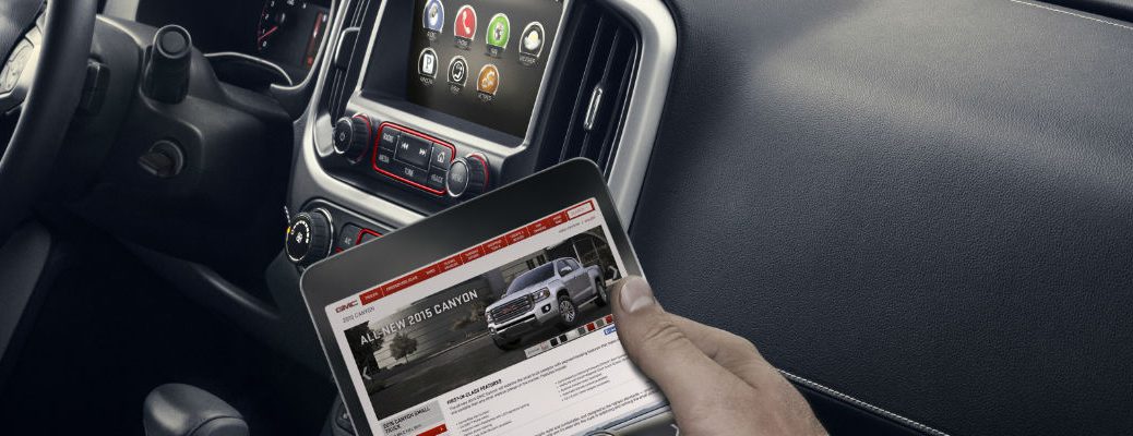 A photo of a person holding a tablet computer that is connected to Wi-Fi in a GMC vehicle