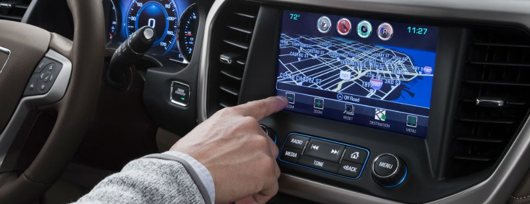 A close up photo of a driver using the GMC infotainment system.