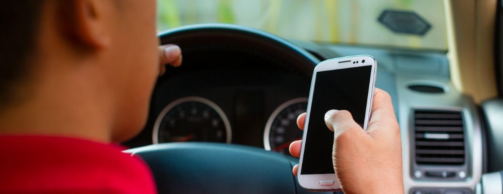 A stock photo of a person using a smartphone while driving.
