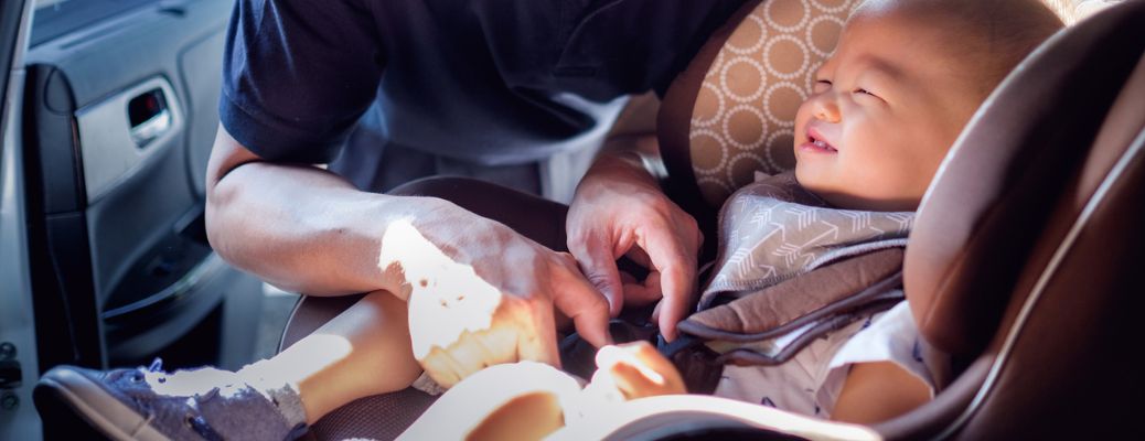Parent fastening a baby in a car seat