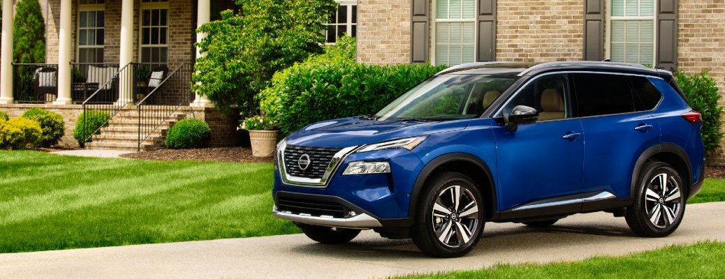A left profile photo of the 2021 Nissan Rogue parked in a driveway.