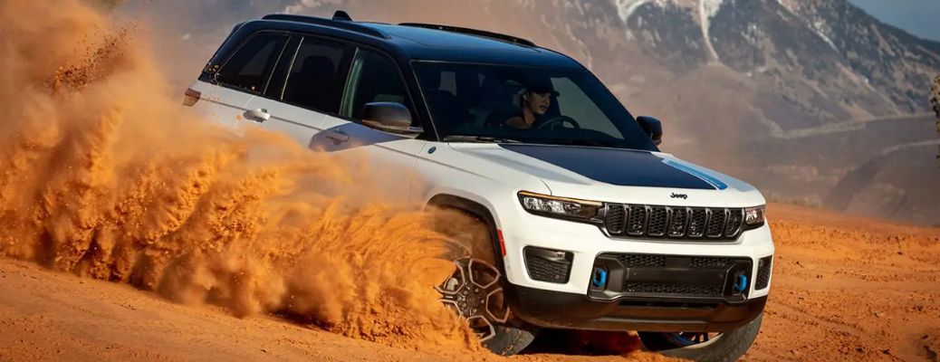 Front three-quarter view of the 2023 Jeep Grand Cherokee dashing through sand
