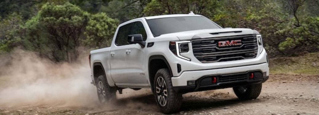 A white 2023 GMC Sierra on a dusty road.