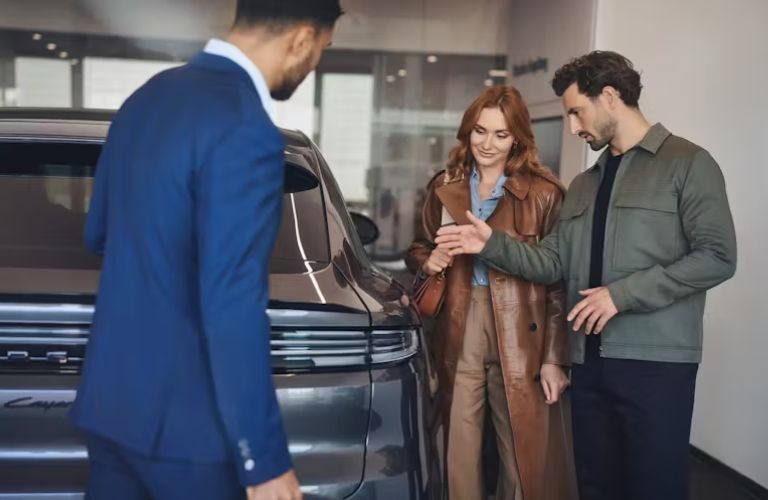 Three people looking at a vehicle