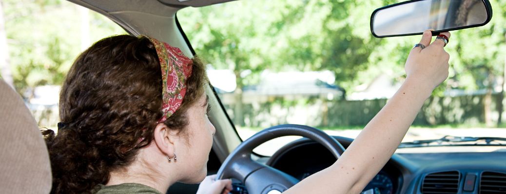 Teen driver adjusting rearview mirror