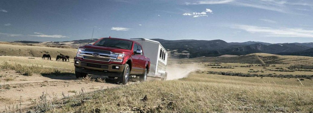 Front exterior view of a red 2018 Ford F-150 hauling a trailer