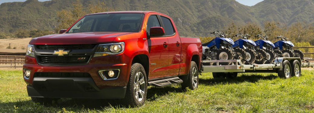 Front exterior view of a red 2018 Chevy Colorado towing ATVs