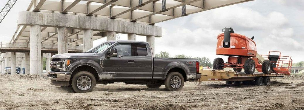 Driver side exterior view of a gray 2018 Ford F-250 hauling heavy equipment