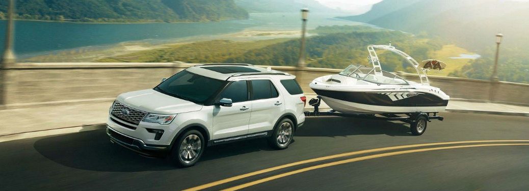 Driver side exterior view of a white 2018 Ford Explorer towing a boat