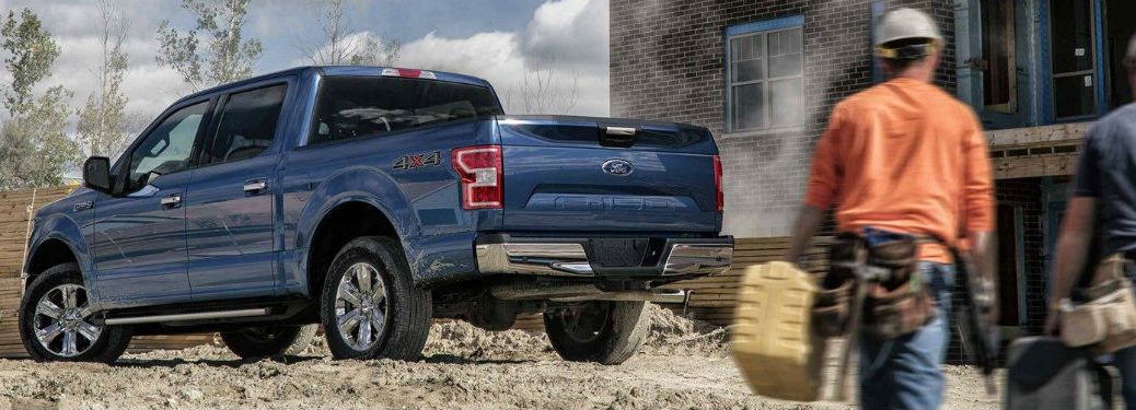 Male worker walking towards a blue 2018 Ford F-150 at a construction site