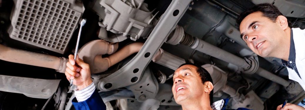 Mechanics inspecting car undercarriage