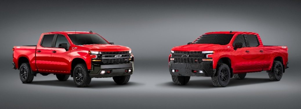 A red Chevy Silverado and red Chevy Silverado made of Legos stand nose to nose.
