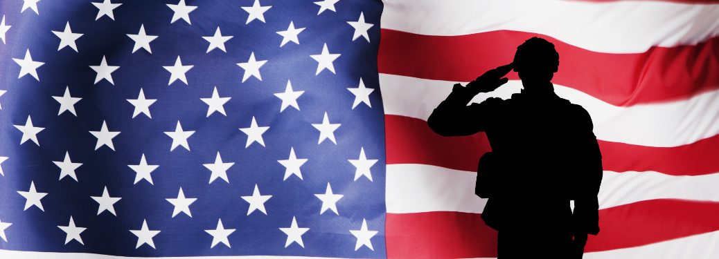 A silhouette of a soldier salutes in front of a beefy American flag