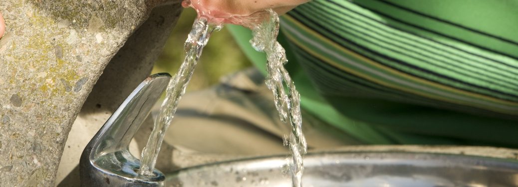 A stream of water from a bubbler makes contact with a pair of lips