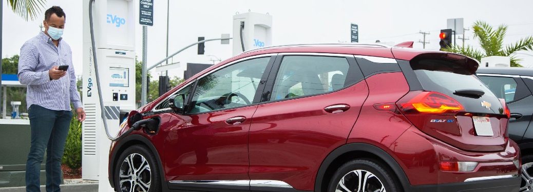 Man in a mask charges a red Chevy Bolt