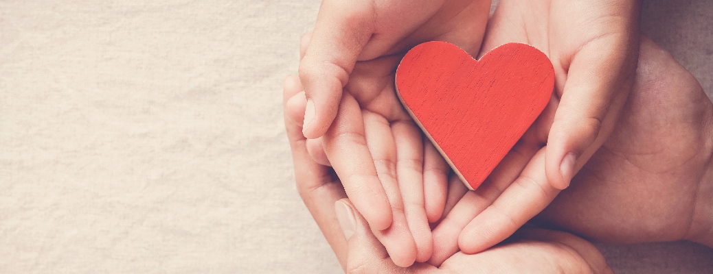 Hands cup a paper heart