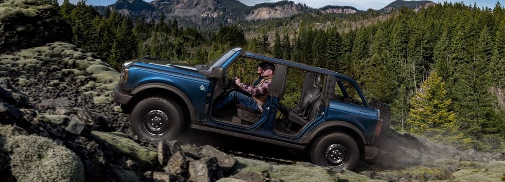 Side view of a blue Ford Bronco offroading