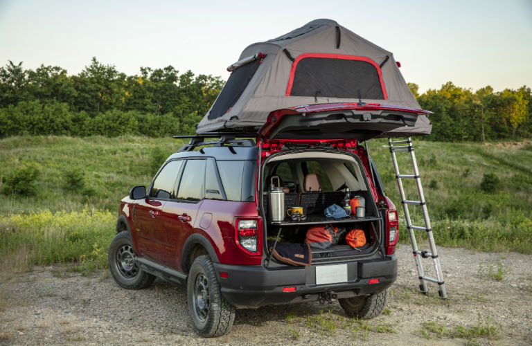 A 2021 Ford Bronco Sport with the rear door open to reveal the interior cargo area and a tent on the roof