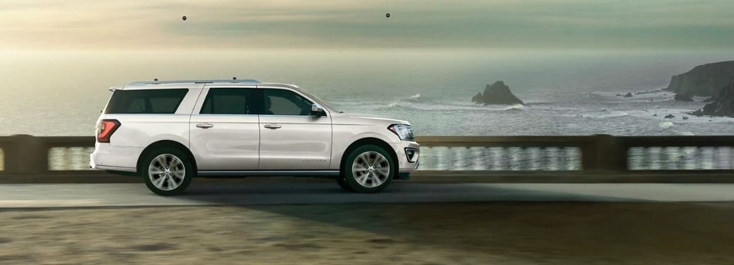 A white 2021 Ford Expedition driving on a bridge in the evening.