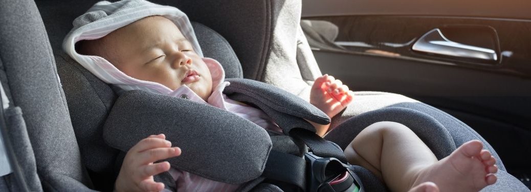 An infant sleeping peacefully in its child safety seat