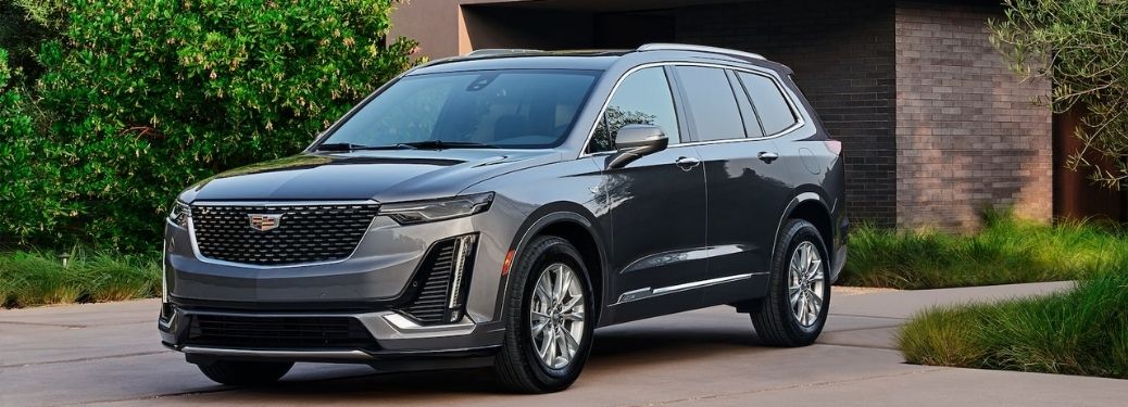 Front quarter side view of a dark grey 2022 Cadillac XT6 parked outside a house