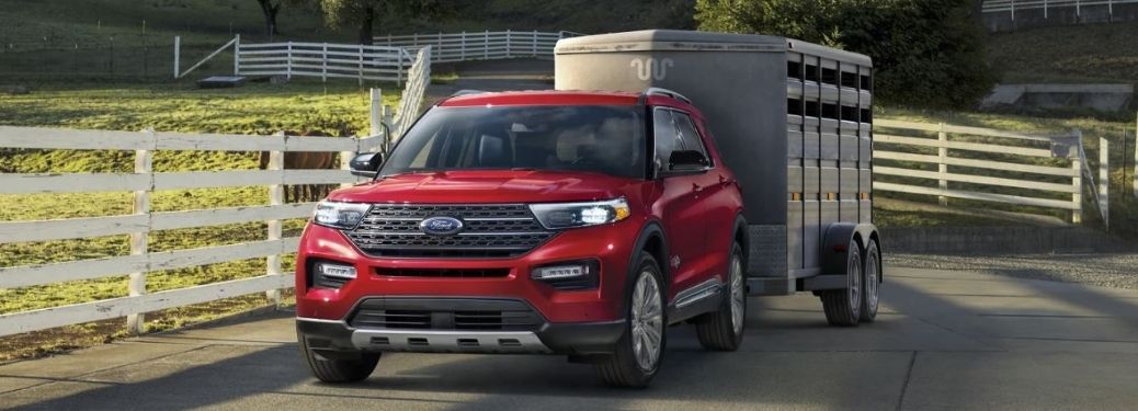 Front side view of a red 2022 Ford Explorer towing a camper trailer